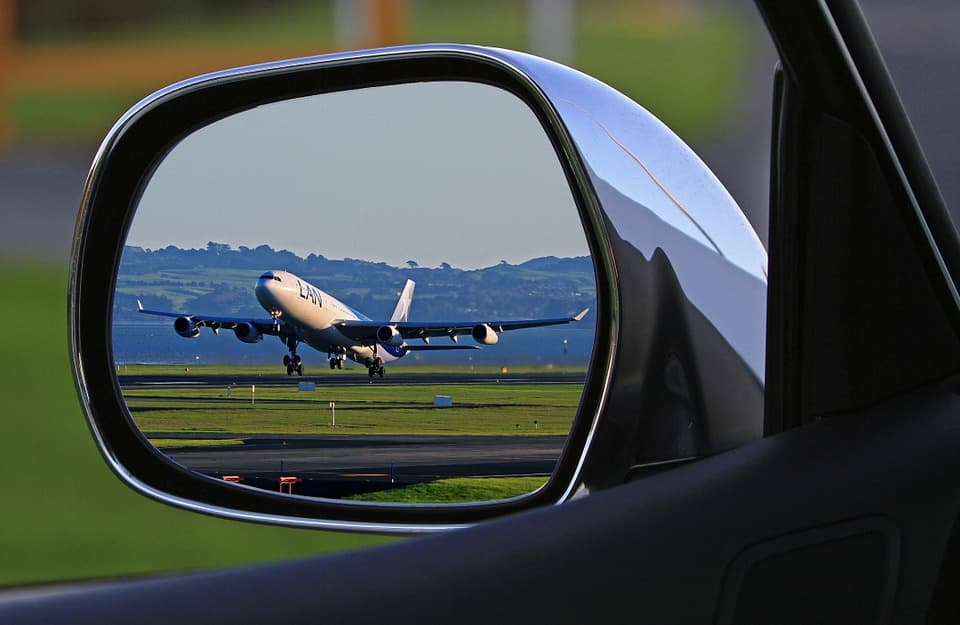 Startendes Flugzeug im Außenspiegel eines Autos