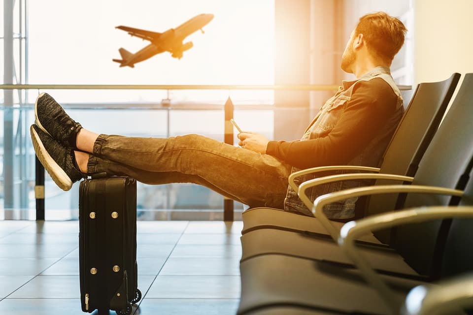 Wartender Passagier am Gate, im Hintergrund ein startendes Flugzeug