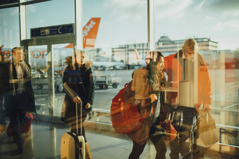 Reisende mit Gepäck vor den Fenstern eines Terminals